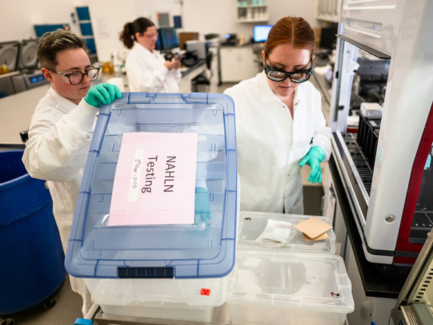 Technicians in a laboratory setting load samples into a transport box as they test milk samples.